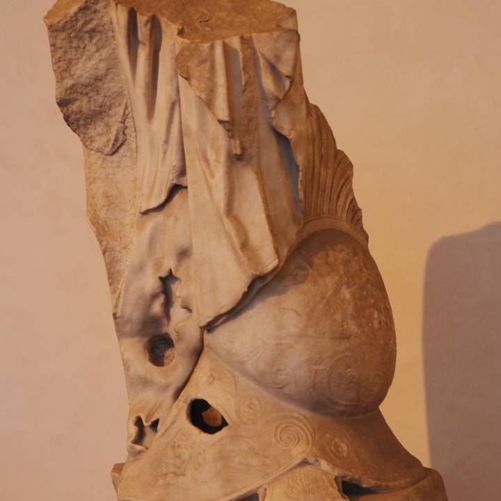 Lower part of a statue with cloak, leaning on a  trunk of a tree and a helmet image